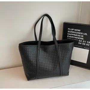 Detailed close-up of a black woven texture large tote bag with elegant shoulder straps