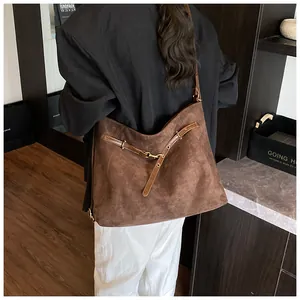 Close-up of vintage brown tote bag featuring suede texture and bronze buckle hardware