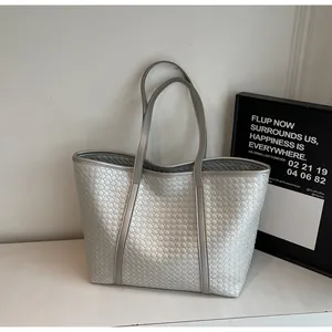 Detail of silver woven tote bag featuring metallic texture and dual shoulder straps
