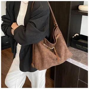 Detail of deep brown suede tote bag showing side metal buckle and leather shoulder strap