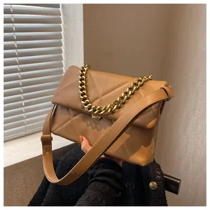 Detail van kakikleurige leren tas met gewatteerde driehoeken en gouden metalen ketting