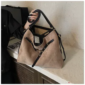 Macro detail of brown suede tote bag with black leather straps and gold metal hardware