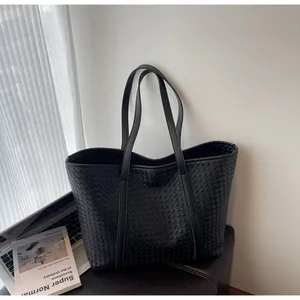 Detail shot of the black woven leather tote bag showing fine grid texture and craftsmanship