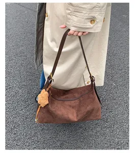 Detail of vintage brown suede hobo bag with leather strap and plush animal charm