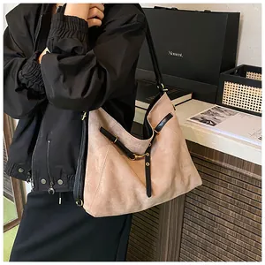 Detailed macro view of beige suede tote bag with black leather straps and gold metal hardware