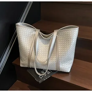 Detail of silver metallic tote bag with intricate woven texture on wooden steps