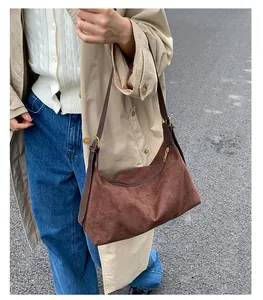 Close-up of brown suede shoulder bag featuring gold hardware and adjustable strap detail