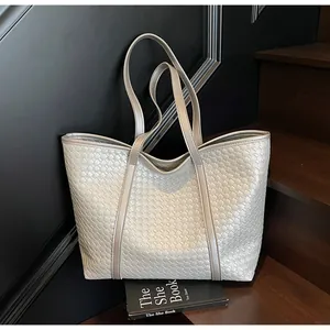 Detail view of the metallic silver woven tote bag texture with slim leather handles