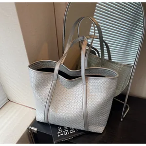 Detail of silver woven tote bag with metallic texture and sleek shoulder straps