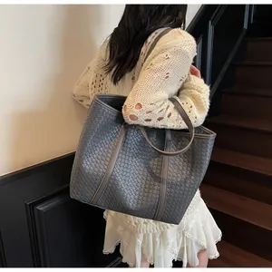 Detailed back view of a grey woven leather tote bag shown in a lifestyle setting