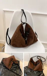 Detalle del bolso tote de ante marrón café con correas negras y herrajes dorados