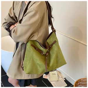 Detail of green suede tote bag with brown leather trim shown on model for daily commute