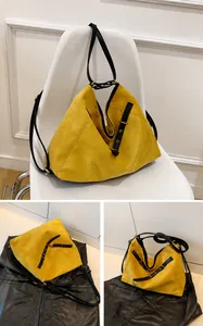 Detalle del bolso tote de ante amarillo con correas de cuero negro y hebilla dorada