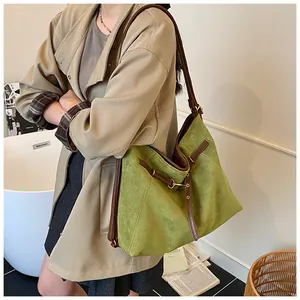 Close-up of moss green suede tote bag with dark brown leather straps and metal buckle