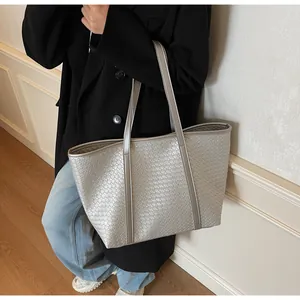 Detail of silver woven leather tote bag with metallic finish shown on a shoulder strap