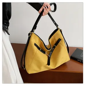Detalle macro del bolso hobo de ante amarillo con correas de cuero negro y aros dorados