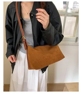 Detail of a brown faux suede crossbody bag with gold adjustable metal buckle and zipper