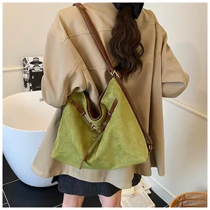 Detail view of large green suede tote bag with brown leather shoulder straps on a model