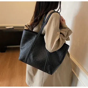Detailed view of black woven tote bag with premium leather texture and long shoulder straps
