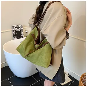 Close-up of green suede tote bag with brown leather strap worn by a person