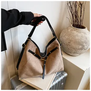 Detail of brown suede tote bag with black leather straps and gold metal hardware