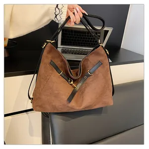 Detalle del bolso tote grande de ante marrón oscuro con correas de cuero negro y hebillas