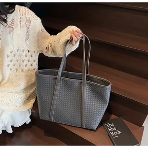 Detailed view of dark grey woven tote bag featuring long straps and synthetic leather texture