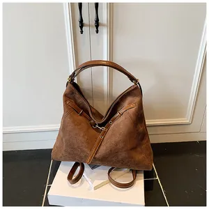 Detailed close-up of brown suede tote bag with leather straps and metal buckle
