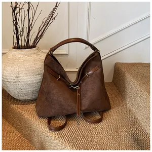 Close-up of a large dark brown suede tote bag with leather strap detail and metal rivets