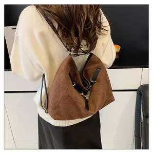 Detalle de mochila de ante marrón con correas negras finas y accesorios dorados