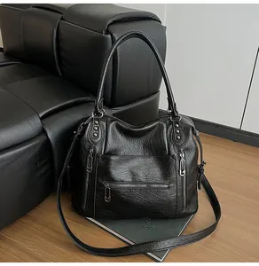 Detailed close-up of a vintage black tote bag with silver rivets and multi-zipper accents