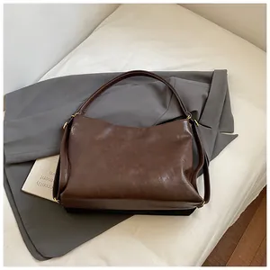 Detail of soft dark brown leather tote bag with elegant gold hardware and long straps