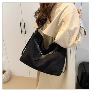 Detalle del bolso tote de lona negra en vista lateral sobre modelo con herrajes dorados