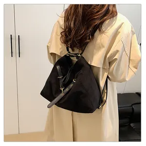 Detalle del bolso tote multifuncional negro con correas de cuero y herrajes dorados