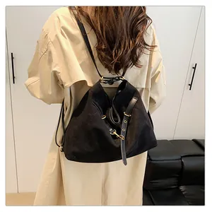 Detalle de un bolso tote negro versátil con herrajes dorados sobre gabardina beige