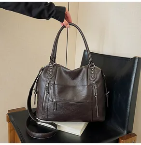 Detail of dark brown vintage tote bag with metal zippers and rivets on a black chair