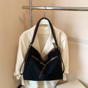 Detail of retro tote bag with black body and dark brown leather straps on a white blazer