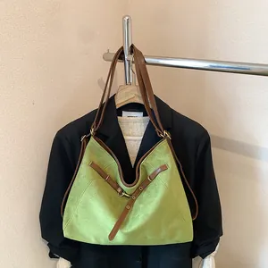 Detail of green suede tote bag with brown leather straps hanging on a blazer