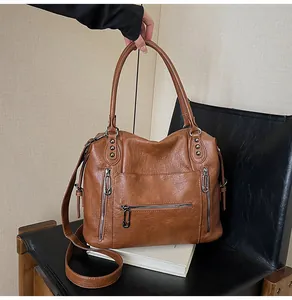Close-up of caramel brown leather tote bag with functional zippers and rivet details