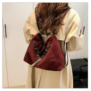 Vista detallada de un bolso tote de ante burdeos con correas negras puesto en modelo