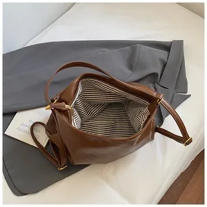 Brown leather tote bag with striped lining and zipper shown on casual blazer outfit