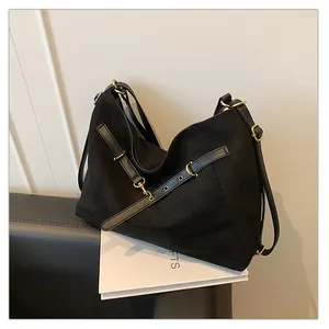 Detalle del bolso tote de ante negro con hebillas de metal dorado y herrajes elegantes