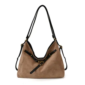 Brown suede tote bag with black leather straps and gold buckles on white background