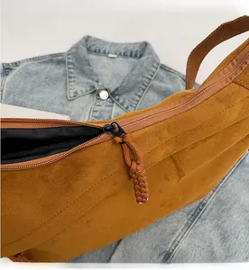 Détail du sac bandoulière en daim caramel avec fermeture éclair noire et tirette tressée