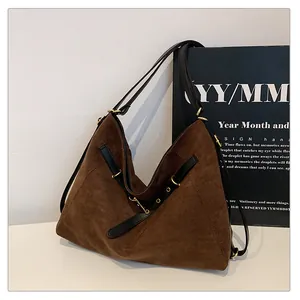 Detalle del bolso tote de ante marrón con ribetes de cuero negro y herrajes dorados