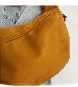 Vue détaillée de la texture en daim doux et du zip du sac demi-lune couleur caramel