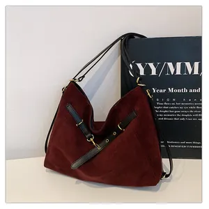 Detalle de bolso tote retro grande en ante rojo oscuro con correa de cuero negro