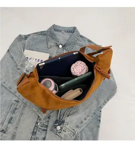 Intérieur spacieux du sac hobo en daim marron contenant une tablette et des objets du quotidien