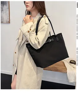 Detail of large black canvas tote bag with silver metal buckle and long leather handles