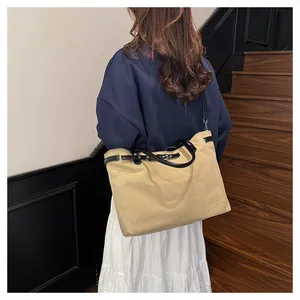 Detailed back view of a large khaki canvas tote bag with black handles on a model